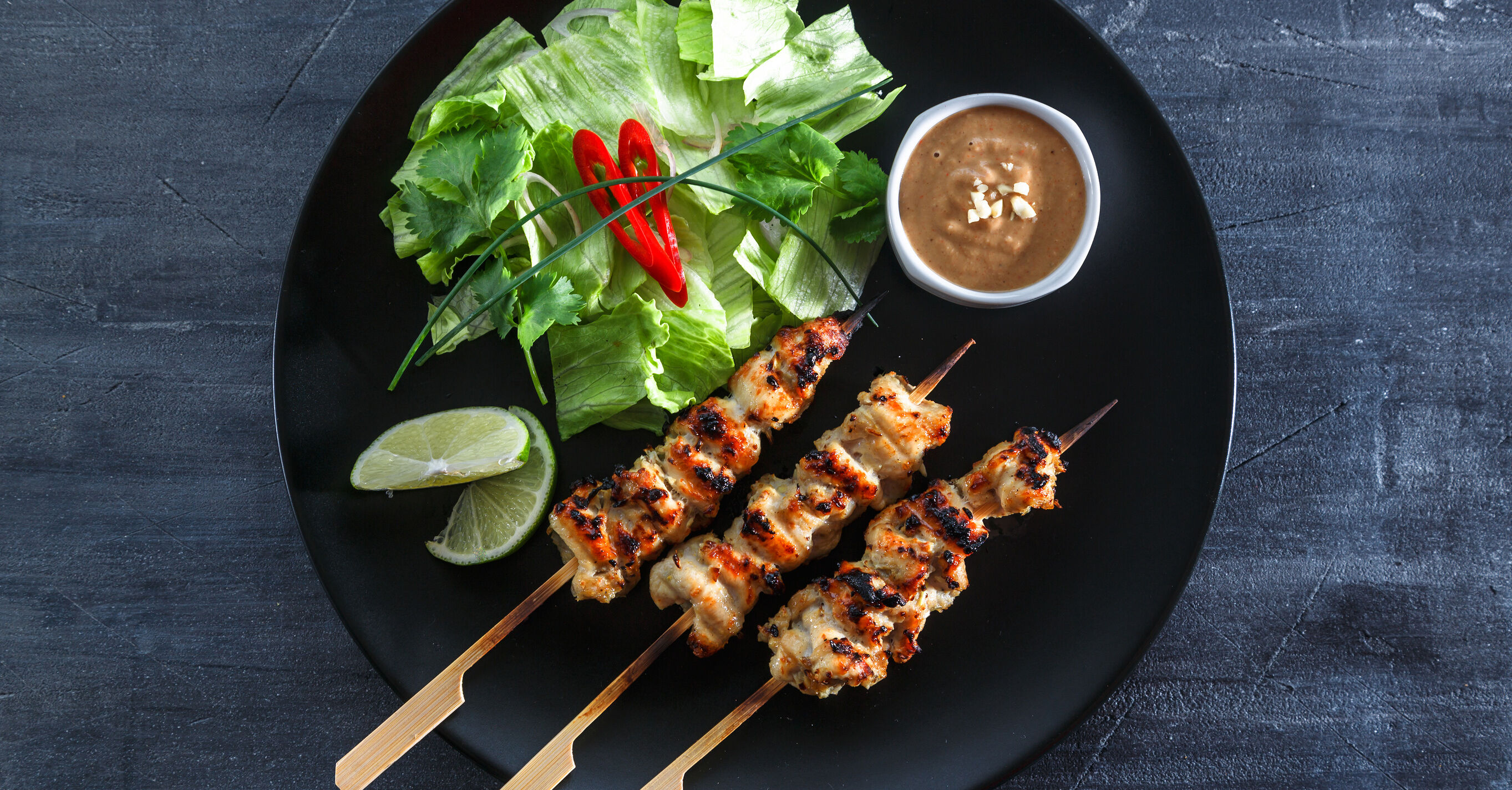 Chicken Satay on a plate with a salad, lime and peanut sauce Chicken Satay on a plate with a salad, lime and peanut sauce