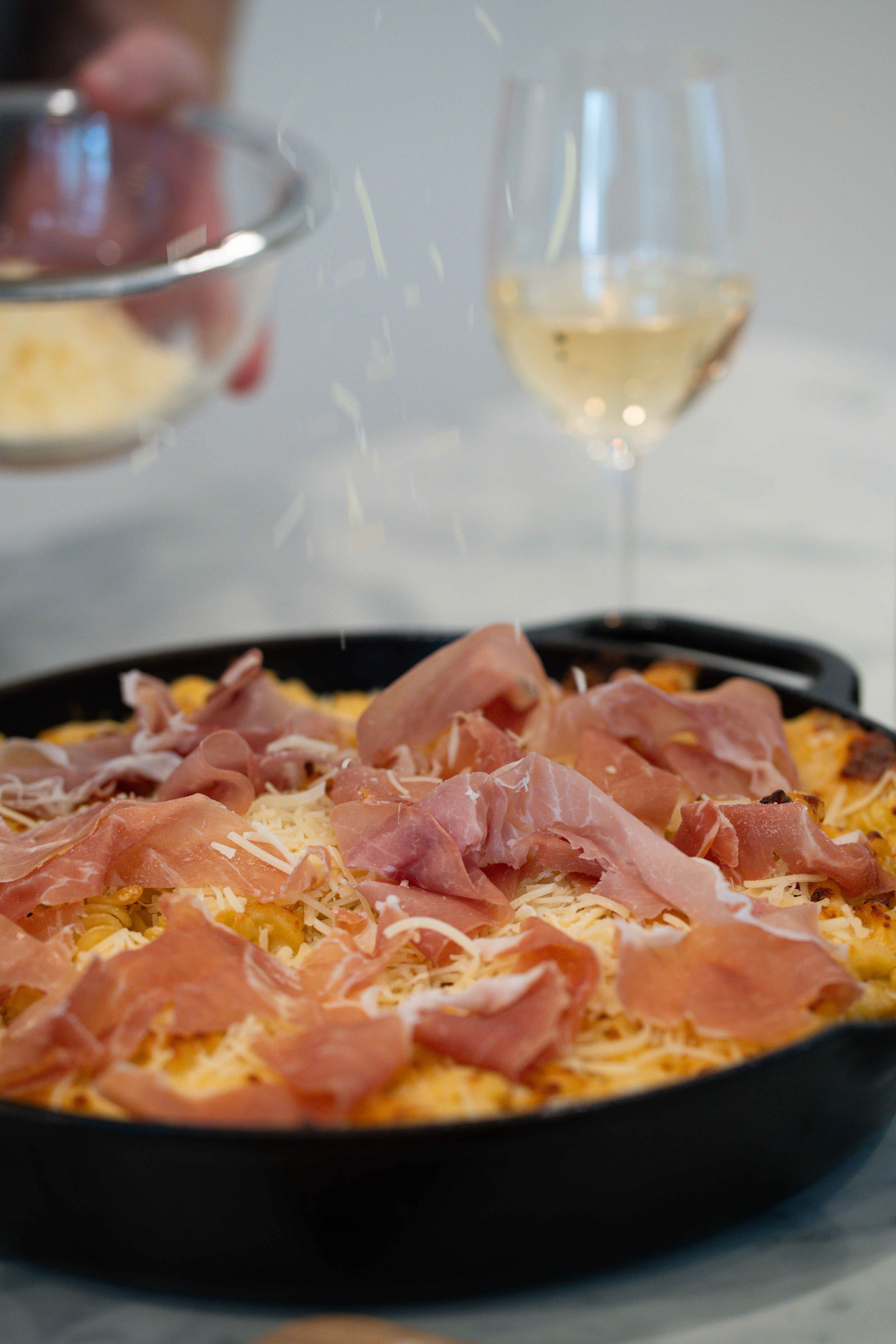 Pouring on Parmesan Cheese on the Cast Iron Mac and Cheese Pouring on Parmesan Cheese on the Cast Iron Mac and Cheese